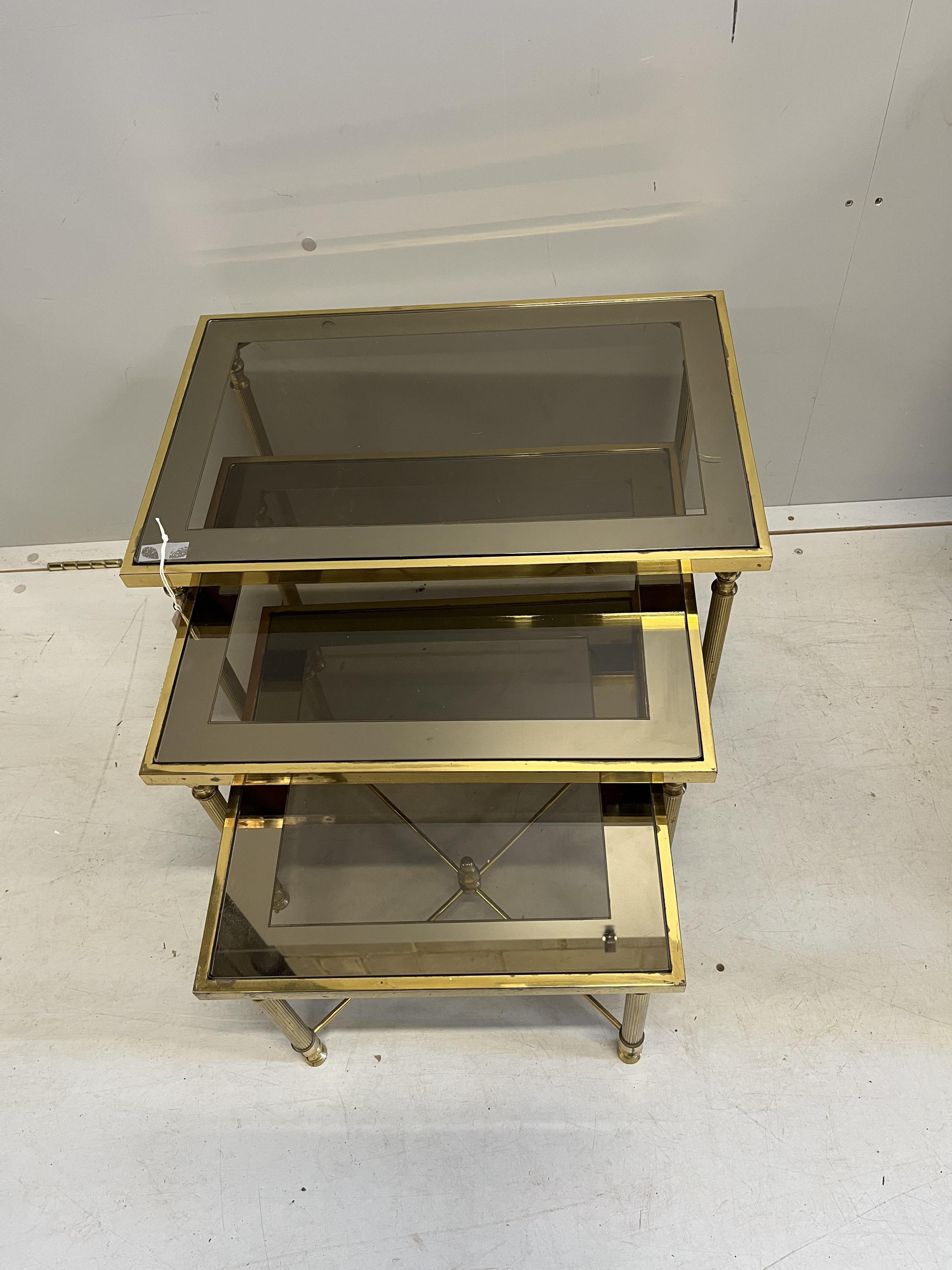 A Maison Jenson style nest of three brass smoked glass tables, width 57cm, depth 37cm, height 40cm